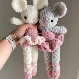 以下が含まれることがあります： ピンクのチュチュとバレエシューズを履いた、手作りのかぎ針編みのネズミが2匹。1匹は白、もう1匹はグレーです。どちらも大きくふわふわの耳と黒い目があります。子供のおもちゃや保育園の装飾に最適な、柔らかくて抱きしめたくなるネズミです。