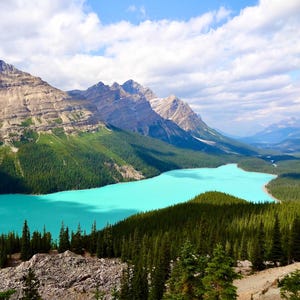 Peut inclure: Un paysage pittoresque avec un lac turquoise entouré de forêts vertes denses et de montagnes imposantes sous un ciel partiellement nuageux. L'image capture une scène naturelle sereine.