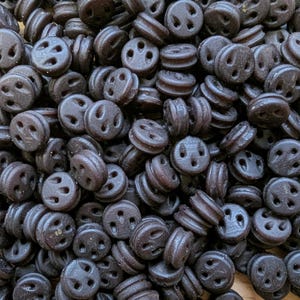 May include: A collection of dark brown, circular buttons. Each button has four holes in a cross shape and a raised edge. These buttons are ideal for various sewing and craft projects. The buttons are approximately 1.5 cm in diameter.