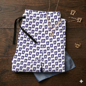 May include: White and navy blue patterned pants with the number 17 repeated throughout. A black drawstring is visible at the waist. Gold necklaces, hairpins, and a ring, all featuring the number 17, are also present.