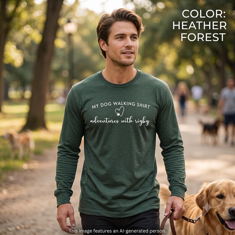 K&ouml;nnte beinhalten: Ein lang&auml;rmeliges Shirt in Heather Forest Gr&uuml;n mit dem wei&szlig;en Text MY DOG WALKING SHIRT, einem Herz- und Pfotenabdruck-Symbol sowie dem Schriftzug adventures with rigby. Das Shirt hat einen Rundhalsausschnitt und eine strukturierte Optik.