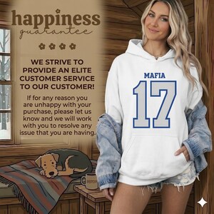 Puede incluir: Sudadera con capucha blanca con la palabra "MAFIA" encima del n&uacute;mero "17" en azul. La sudadera tiene un bolsillo de canguro y una capucha con cord&oacute;n. La imagen tambi&eacute;n incluye el texto "happiness guarantee" y "WE STRIVE TO PROVIDE AN ELITE CUSTOMER SERVICE TO OUR CUSTOMER!"