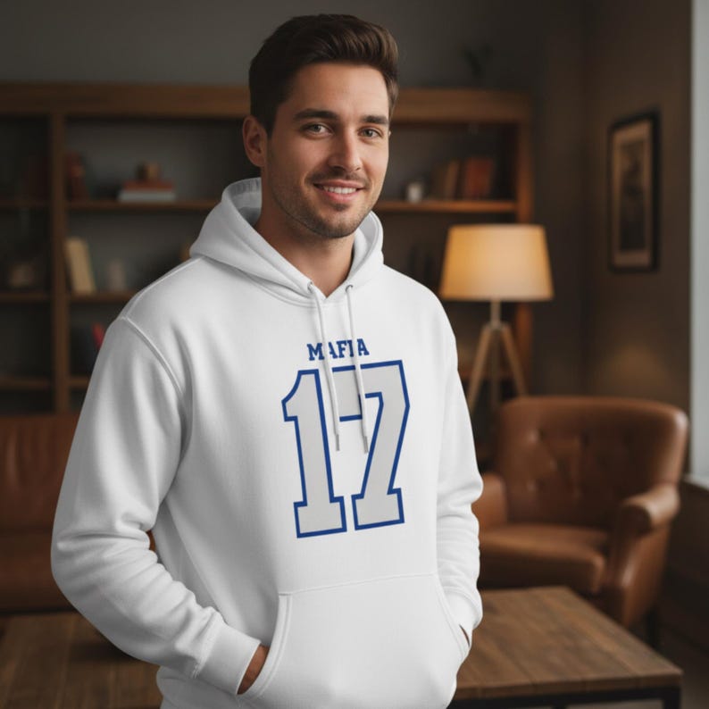 Puede incluir: Sudadera con capucha blanca con bolsillo delantero y cord&oacute;n. La sudadera presenta la palabra "MAFIA" encima del n&uacute;mero "17" en un dise&ntilde;o azul y blanco. Hecha de un material suave.