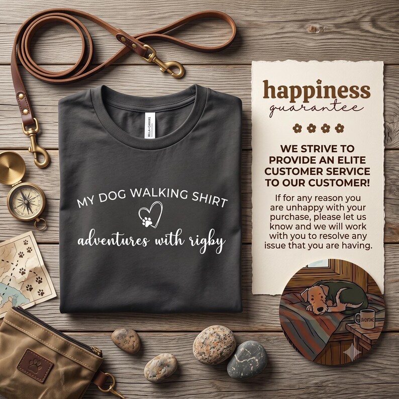 K&ouml;nnte beinhalten: Ein dunkelgraues T-Shirt mit dem wei&szlig;en Text MY DOG WALKING SHIRT und adventures with rigby sowie einem Herz- und Pfotenabdruck-Symbol. Das T-Shirt wird zusammen mit einer braunen Lederleine, einem Kompass, einer Karte, einem Beutel und einer Karte gezeigt.