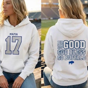 Puede incluir: Sudadera con capucha blanca con bolsillo delantero. La parte delantera presenta "MAFIA" sobre el n&uacute;mero "17" en azul. La parte trasera muestra "BE DO GOOD GOD BLESS GO BUFFALO" con un logotipo de b&uacute;falo azul.