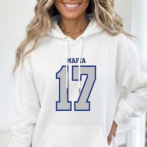 Puede incluir: Sudadera con capucha blanca con la palabra "MAFIA" encima del n&uacute;mero "17" en un dise&ntilde;o azul y gris. La sudadera tiene una capucha con cord&oacute;n y un bolsillo delantero.