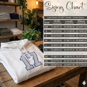 Puede incluir: Una sudadera con capucha unisex blanca con la palabra "MAFIA" y el n&uacute;mero "17" en azul. La imagen incluye una tabla de tallas con medidas en pulgadas y cent&iacute;metros para las tallas XS, S, M, L, XL, 2XL y 3XL.