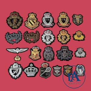 May include: A collection of embroidered patches in various shapes and designs, including crowns, crests, and wings. The patches feature gold, silver, black, and white thread on a red background. Some patches have text, such as "ASILE" and "TR".