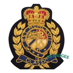 Pode incluir: Um patch bordado azul marinho com uma coroa dourada, folhas de louro e um emblema central. O emblema apresenta um design azul e vermelho com detalhes dourados. A palavra "CLASSIC" é bordada em ouro em uma faixa azul.