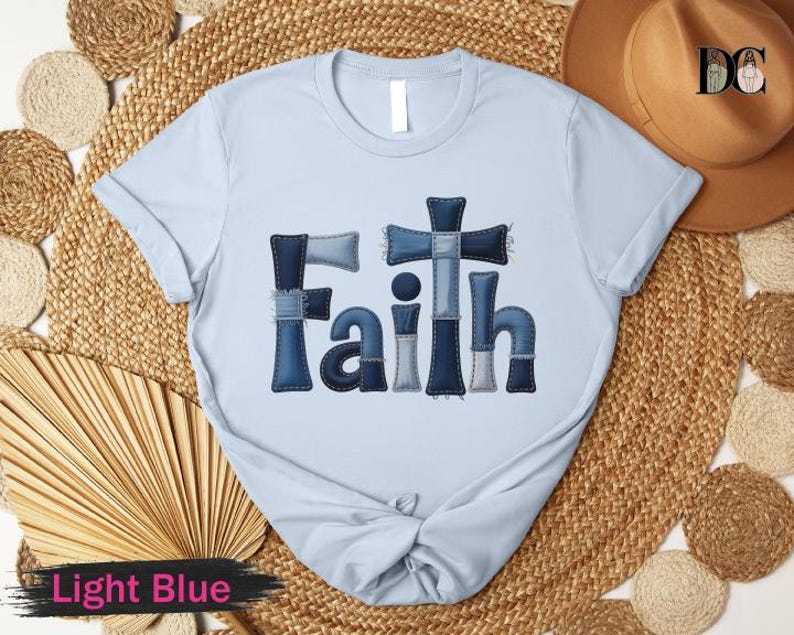 A light blue t-shirt with the word "Faith" printed on it, along with a straw hat and a fan, all arranged on a woven mat.