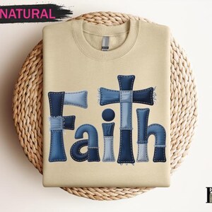 A beige t-shirt with the word "Faith" written in blue letters, along with a cross design, is displayed on a woven placemat.