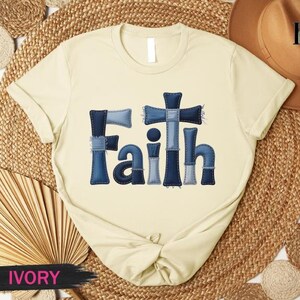 A beige t-shirt with the word "Faith" printed in blue denim-like letters, placed on a woven mat.
