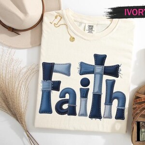 a white t-shirt with a blue cross-shaped design, a beige hat, a pair of sandals, and some decorative elements on a white background.