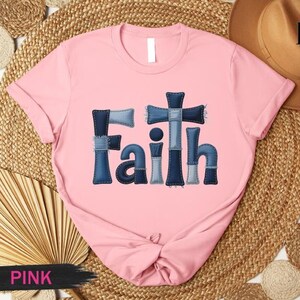A pink t-shirt with the word "Faith" printed in blue denim jeans-like letters, placed on a woven mat.