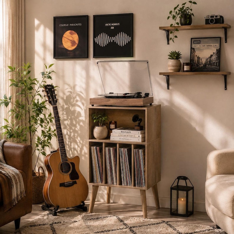 May include: A light brown wooden record player stand with four vertical storage compartments for vinyl records, a top shelf for a turntable, and a middle shelf holding books. The stand features tapered legs and a natural wood grain finish.