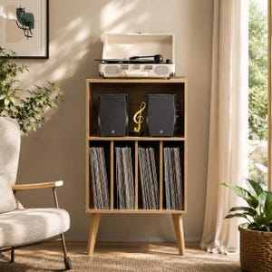May include: A light brown wooden record storage cabinet with four vertical compartments for vinyl records, two black speakers, and a gold treble clef ornament on the middle shelf, topped with a cream-colored portable record player.