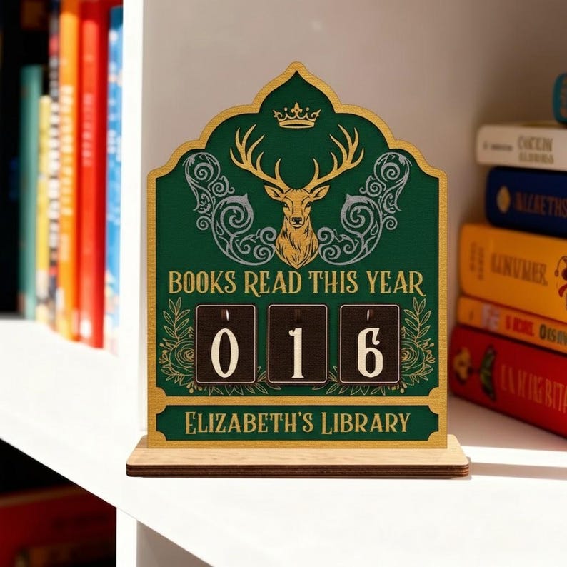 May include: A wooden desk calendar with a green background and gold detailing. The calendar reads "BOOKS READ THIS YEAR" and displays "016". A deer head and crown are at the top. The text "ELIZABETH'S LIBRARY" is at the bottom.