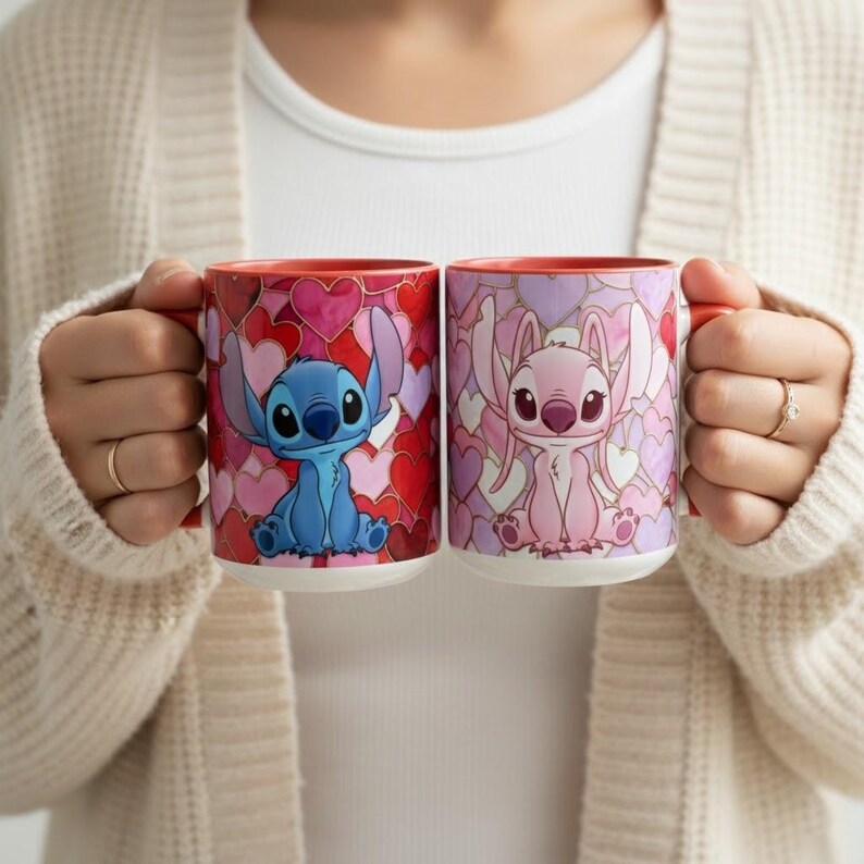 May include: Two ceramic mugs featuring Stitch and Angel characters. The mugs have red handles and interiors. The exterior of each mug is decorated with a heart pattern in shades of red, pink, and purple. The mugs are held up by a person.