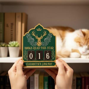 May include: A green and gold wooden book counter with the text "BOOKS READ THIS YEAR" and the number "016". The counter features a deer illustration and the text "ELIZABETH'S LIBRARY".