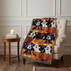 May include: A woven throw blanket featuring a repeating Halloween pattern with Mickey Mouse dressed as a wizard, white ghosts, orange jack-o'-lanterns, purple bats, yellow stars, and candy corn on a black and orange striped background.
