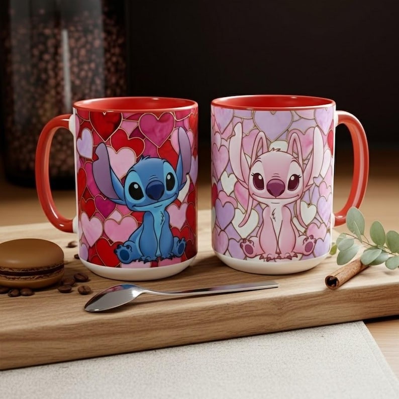 May include: Two ceramic mugs with red handles and interiors. One mug features a blue cartoon character on a background of red and pink hearts. The other mug has a pink cartoon character on a background of pink and purple hearts.
