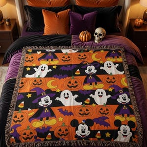 May include: A rectangular woven throw blanket featuring a repeating Halloween pattern of Mickey Mouse dressed in a purple witch hat and cape, white ghosts, orange jack-o'-lanterns, purple bats, yellow stars, and candy corn on orange and black stripes.