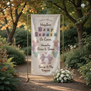 May include: A cream-colored baby shower banner with gold metal stand. The banner reads "Join us for the Happiest Baby Shower on Earth. Honoring Olivia & Tomas." Mickey Mouse silhouettes and balloons are featured.