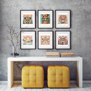 May include: A gallery wall featuring six framed art prints with Day of the Dead skull designs. The artwork showcases colorful floral arrangements and intricate details. The wall decor is set above a white console table with two yellow cube ottomans.