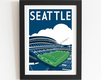 May include: A framed art print featuring a stylized illustration of a football stadium in Seattle. The image displays a green field, dark blue stadium seating, and white clouds against a dark blue sky. The word SEATTLE is printed in white.