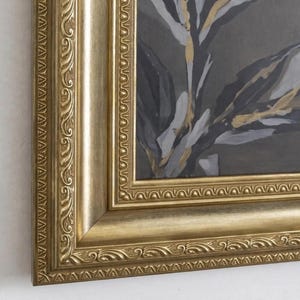 以下が含まれることがあります： ダークグレーの背景に白と金の抽象的な葉の模様が描かれた長方形のウォールアート。作品は、複雑なエンボス加工のスクロール模様とビーズ状の縁取りが施された、幅広で装飾的なゴールドのフレームに収められています。