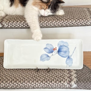 May include: A white ceramic mug with a black handle and the text "But First, Coffee" in a black, handwritten-style font. The mug is on a white surface.