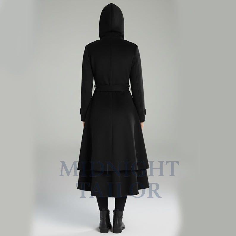 以下が含まれることがあります： フード、ベルト、フレアスカートが付いた黒のロングコート。コートは二層構造のスカートデザインで、黒のレギンスとブーツを着用しています。背面図は、コートのテーラードシルエットと詳細を示しています。