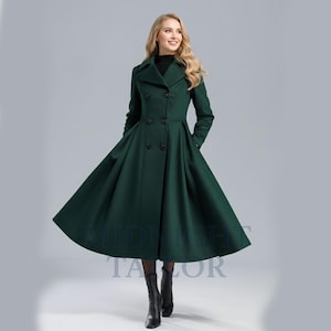 May include: A long, emerald green coat with a double-breasted design and a flared skirt. The coat features a notched collar, long sleeves, and black buttons. The text "MIDNIGHT TAILOR" is visible at the bottom of the coat.