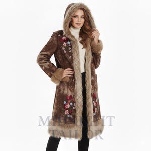 May include: A long brown coat with a faux fur-lined hood and trim. The coat features floral embroidery in shades of red, pink, and blue. The coat has a textured pattern and is knee-length.