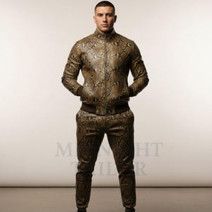 Könnte beinhalten: Zweiteiliges Outfit mit Schlangenmuster. Die Jacke hat einen Reißverschluss und Taschen, mit braunem Rippsaum und Bündchen. Die passende Hose hat ein ähnliches Schlangenmuster. Das Outfit ist braun und beige.