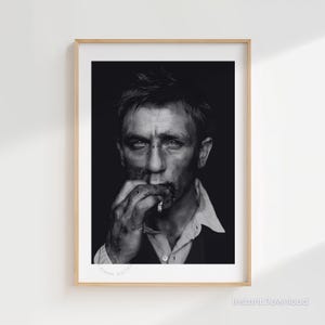 May include: Black and white portrait print of a man with a cigarette in his mouth. The image is framed in a light wood frame. The man is wearing a white collared shirt and a dark jacket. The image has the words "Instant Download" at the bottom.