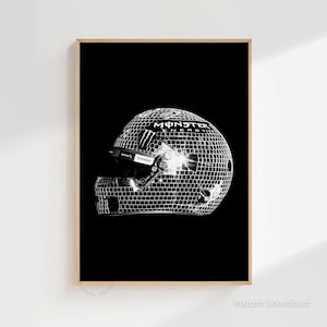 May include: Black and white print of a racing helmet with a mirrored disco ball effect. The helmet features the Monster Energy logo and a visor. The image is set against a black background and framed in a wooden border.