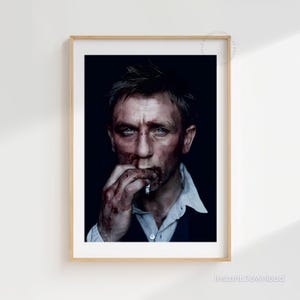 May include: A framed portrait featuring a man with blue eyes, blood on his face and hands, and a cigarette in his mouth. He is wearing a white collared shirt and a dark suit jacket. The background is dark.