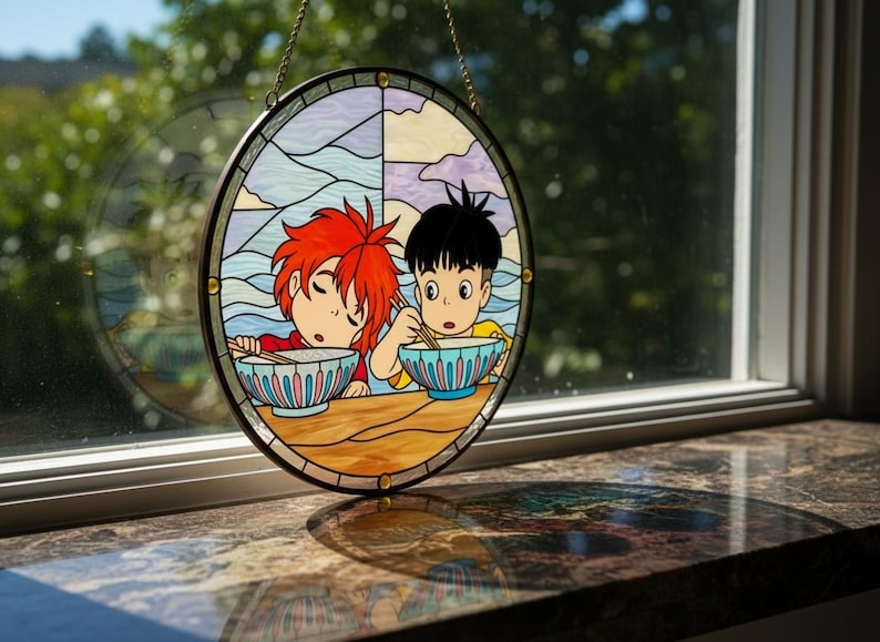 May include: Circular stained glass artwork depicting two anime-style figures enjoying a meal. The design incorporates vibrant colours, including blue, red, yellow, and purple. The glass is framed with a black border and a gold chain for hanging, suitable for a window.
