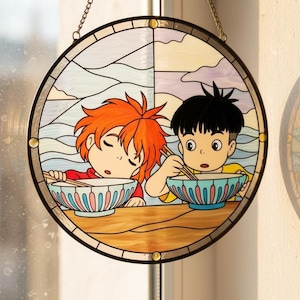 May include: Circular stained glass window depicting two cartoon children eating from bowls with chopsticks. One child has orange hair and is asleep. The other child has black hair and is awake. The background shows a landscape with clouds and mountains.