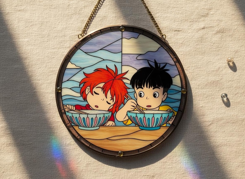 May include: Circular stained glass artwork depicting two anime-style figures eating from bowls. The piece has a brown border and a chain for hanging. The background shows a sky and ocean scene.
