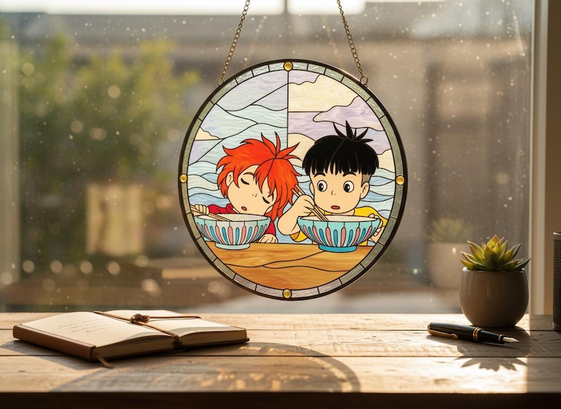 May include: A circular stained glass window panel depicting two anime-style figures enjoying ramen. The artwork uses blue, yellow, and red hues, with a black border and a hanging chain. The panel is displayed in front of a window.