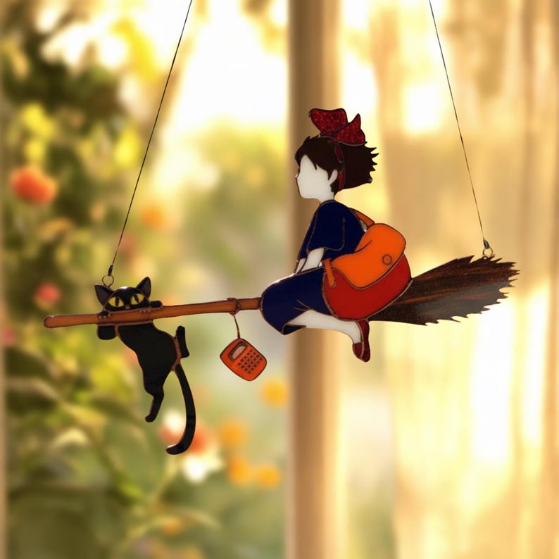 May include: A whimsical stained glass suncatcher featuring a young witch riding a broom with a black cat and a phone. The witch wears a blue dress, red bow, and carries an orange backpack. The cat hangs on the broom.
