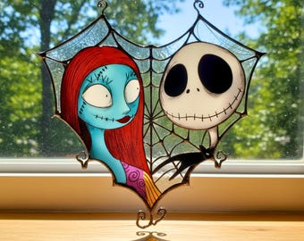 Puede incluir: Vidriera con Sally y Jack Skellington de Pesadilla antes de Navidad. Sally tiene piel azul, cabello rojo y rasgos cosidos. Jack es un esqueleto blanco con una sonrisa cosida. También hay un gato negro.