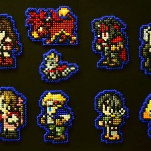 May include: Pixel art character magnets featuring characters from Final Fantasy. The magnets are in various colors, including yellow, red, and blue, with a blue border. The characters are in a variety of poses.