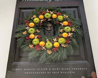 May include: A hardcover book titled Williamsburg Christmas by The Colonial Williamsburg Foundation, authored by Libbey Hodges Oliver and Mary Miley Theobald, with photography by Erik Kvalsvik. The cover features a green wreath with apples.