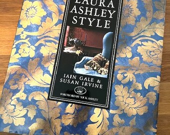May include: A blue and gold book with the title "Laura Ashley Style" by Iain Gale & Susan Irvine. The book cover features a gold floral pattern on a blue background.