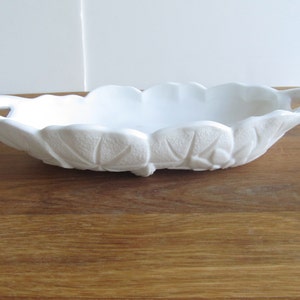May include: White ceramic serving bowl with two handles and a scalloped edge. The bowl has a floral design.