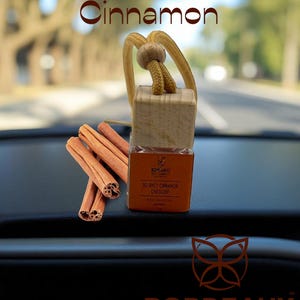 May include: An air freshener with the text "So Spicy Cinnamon" and a car scent label. The air freshener is made of wood and has a hanging cord. Cinnamon sticks are placed next to the air freshener. The brand name "Bordeaux" is at the bottom.