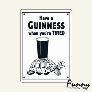 May include: A black and white sign with the text "Have a Guinness when you're TIRED". The image shows a pint of Guinness balanced on a turtle's shell. The words "Funny Engraving" are in the bottom right corner.